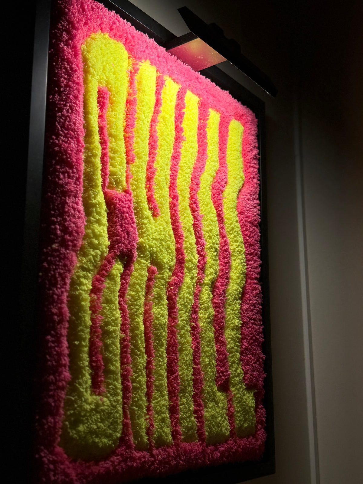 CHILL, œuvre tuftée contemporaine rose et jaune de Ninon Dechavanne, présentée dans sa caisse américaine noire rétroéclairée.